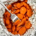 A fork is holding carrots in foil.