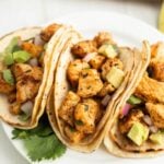 Grilled chicken tacos with avocado and cilantro on soft flour tortillas.