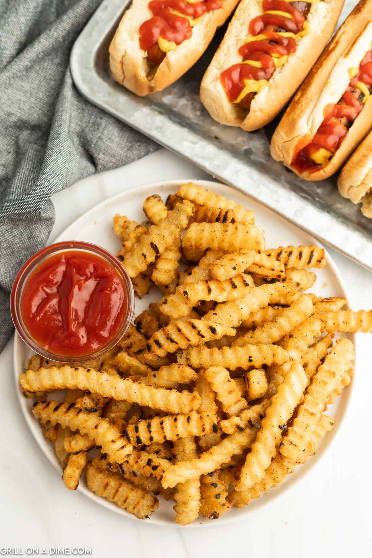 Golden brown Fries on a which plate with a small bowl of ketchup. 