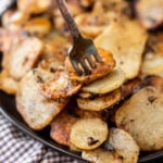 A fork is lifting potatoes from a pan.