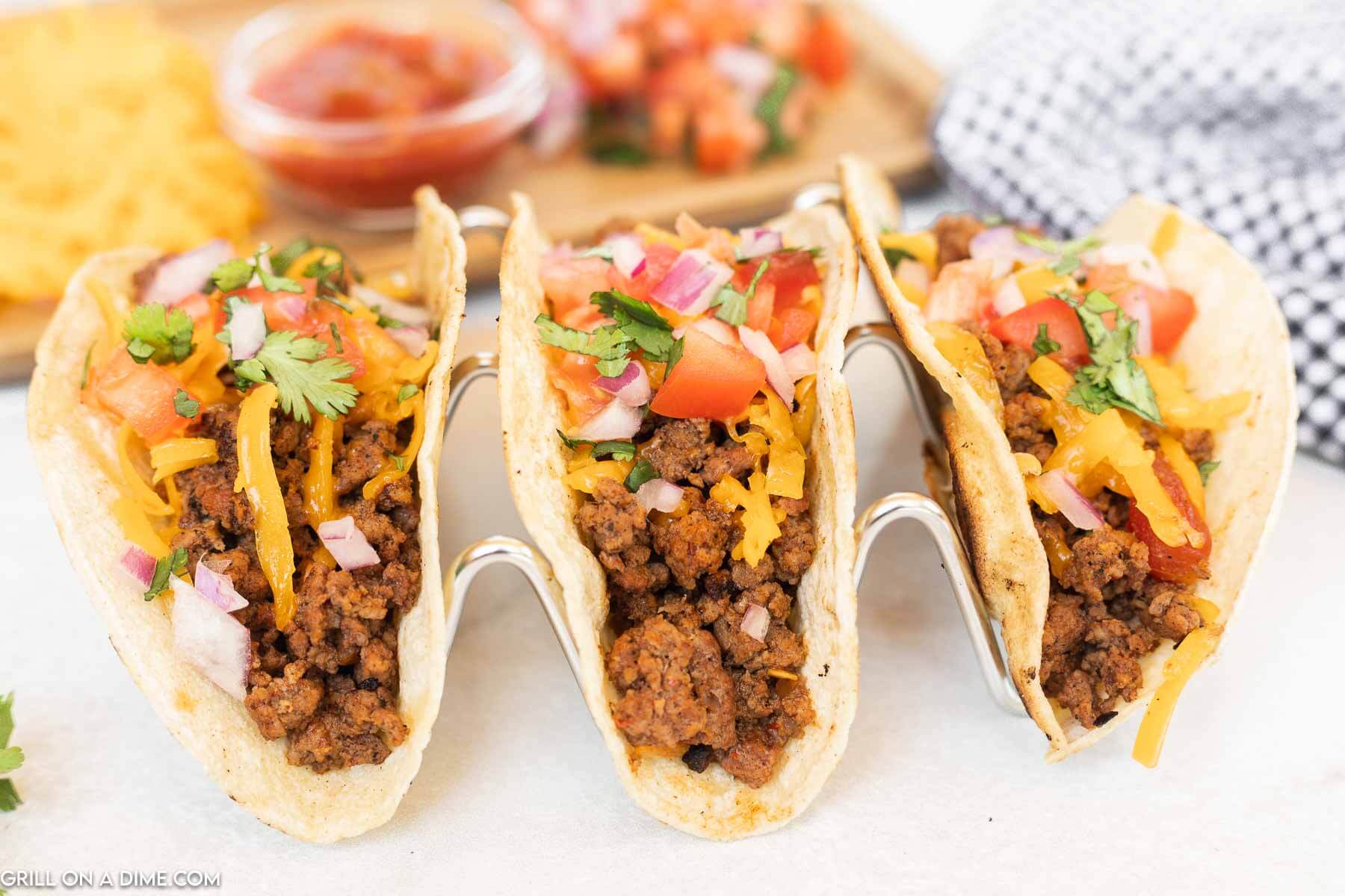 Ground Beef Tacos in a taco stand topped with pico de gallo and cheese