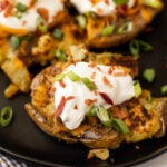 Two baked potatoes topped with sour cream and bacon.