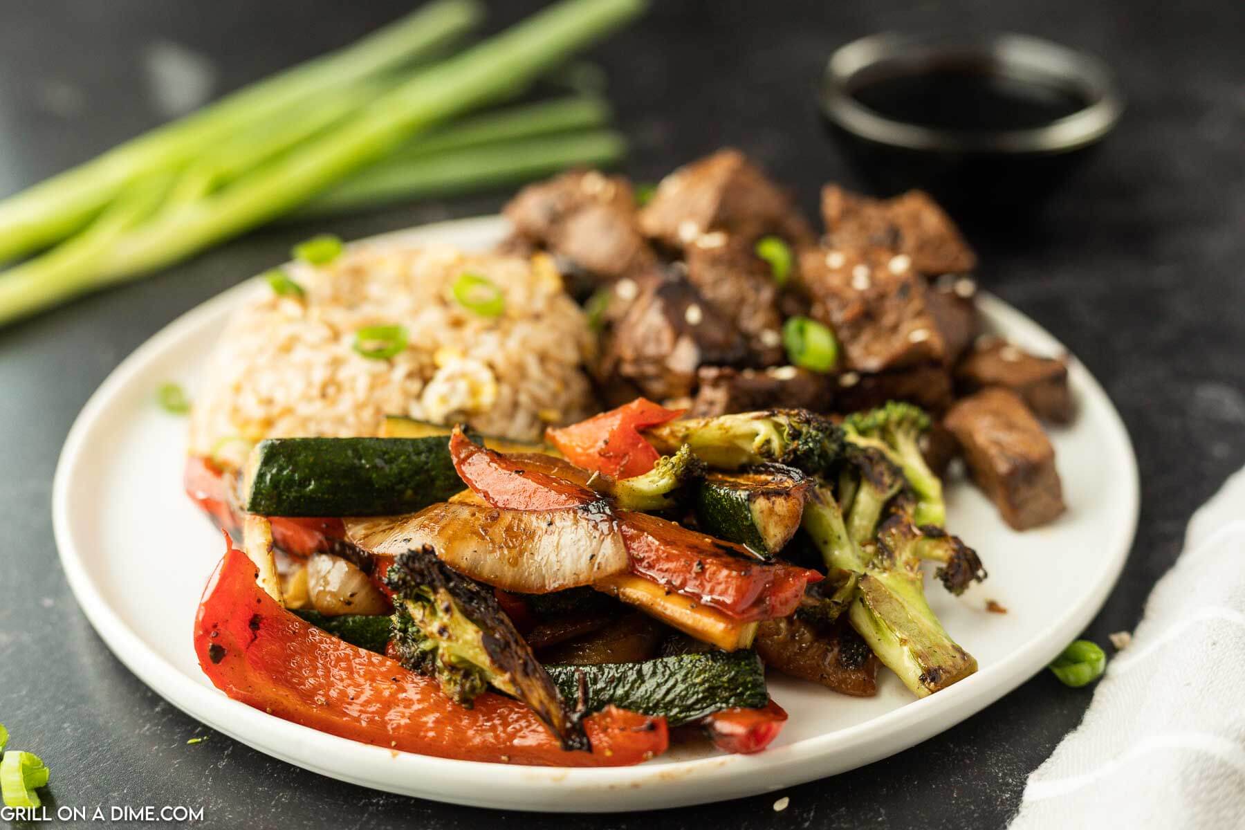 Hibachi veggies on a plate with steak bites and fried rice