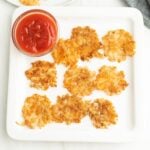 A plate with some smashed potato and ketchup.