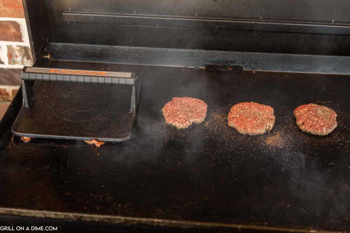 Cooking burgers on the griddle with a burger press.