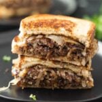 Patty Melt cut in half stacked on a black plate