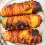 Grilled corn on the cob wrapped in bacon, cooked to perfection with smoky char flavor.