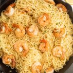 A skillet filled with spaghetti and shrimp.