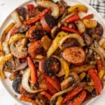 A plate of sausage, peppers and onions.