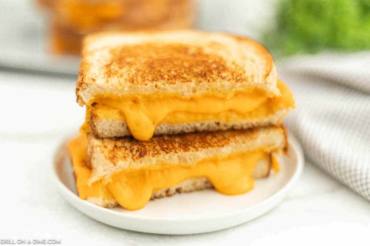 Blackstone Grilled Cheese cut in half stacked on a plate.