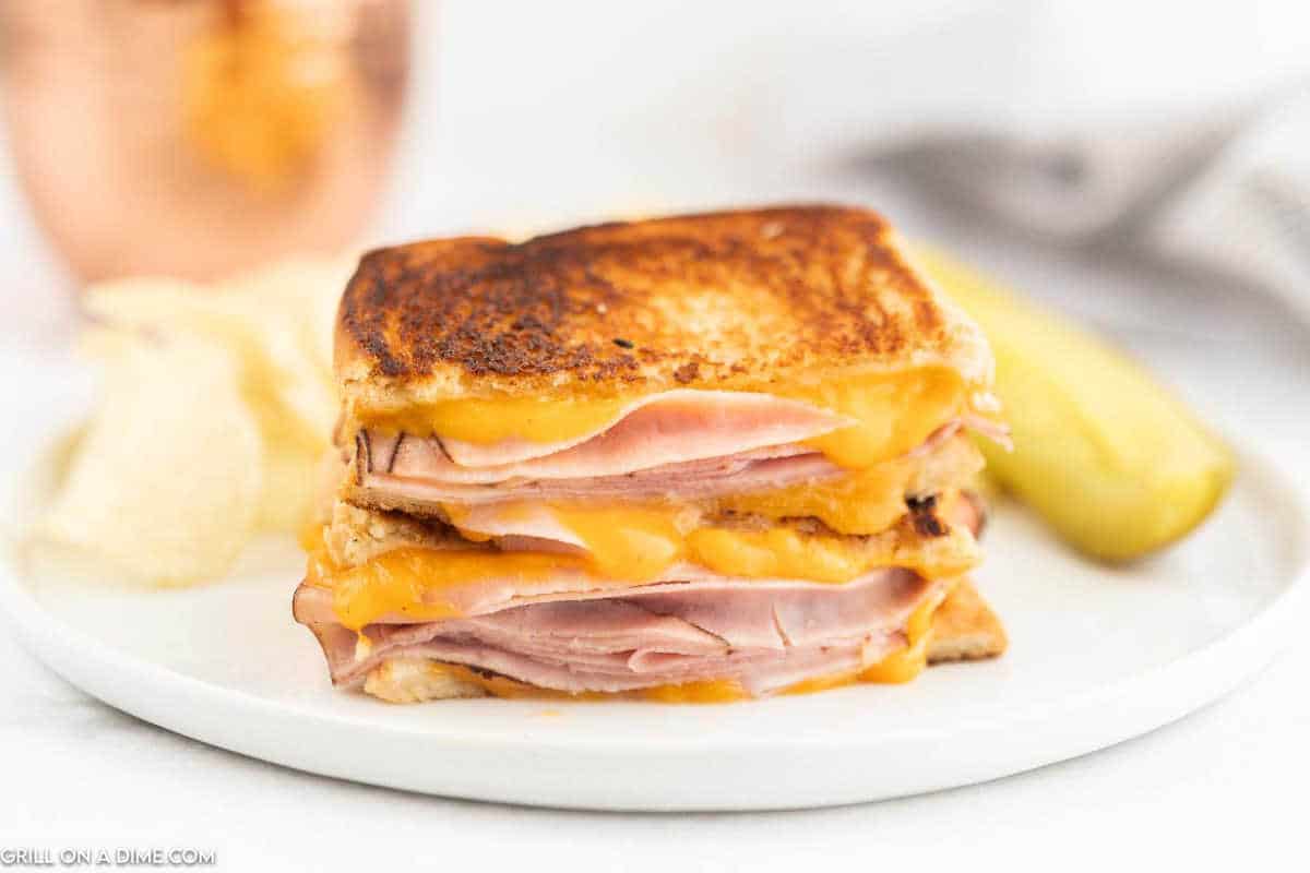 Grilled ham and cheese cut in half stacked on a plate.