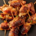 Grilled bacon-wrapped dates with crispy edges and fresh herbs for flavorful appetizers or mains.