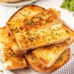 Grilled garlic bread slices on a white plate.