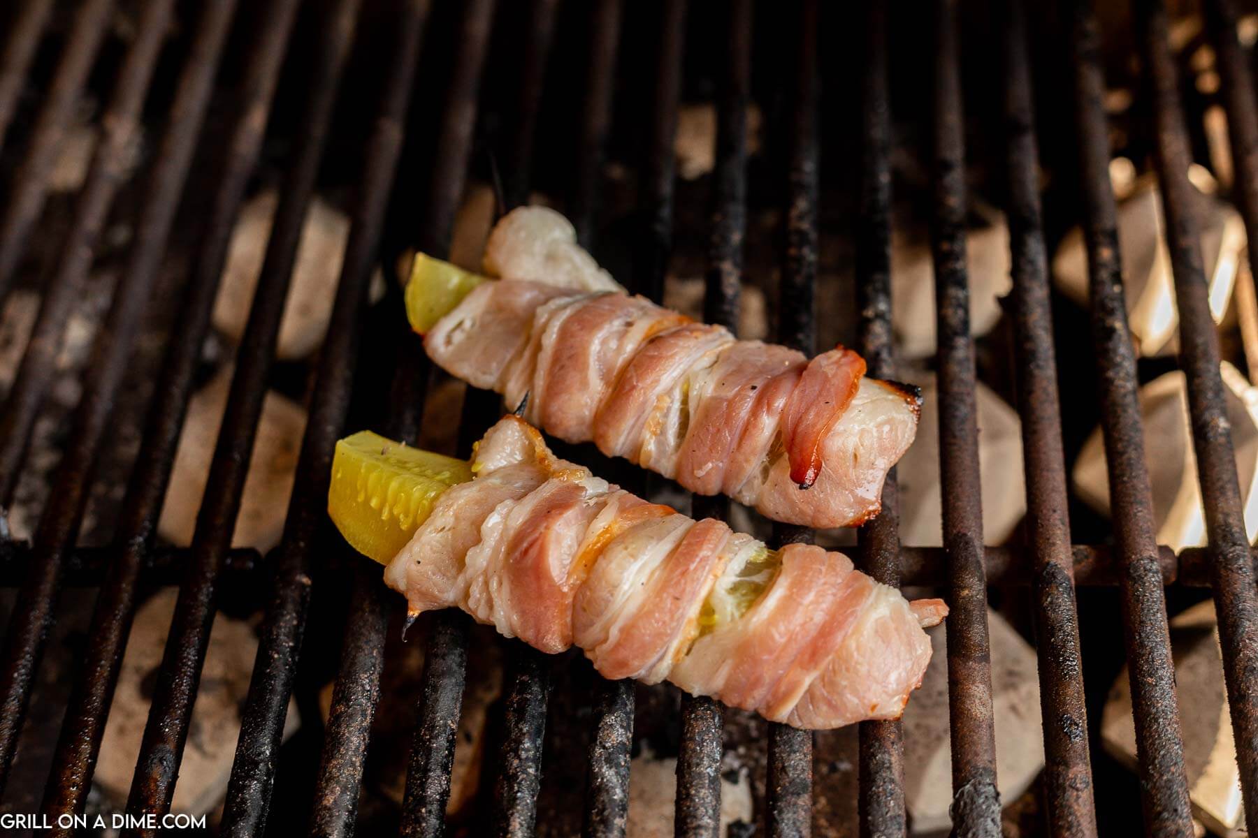 Grilled bacon-wrapped jalapeno poppers on a white plate, fresh and smoky for appetizers.