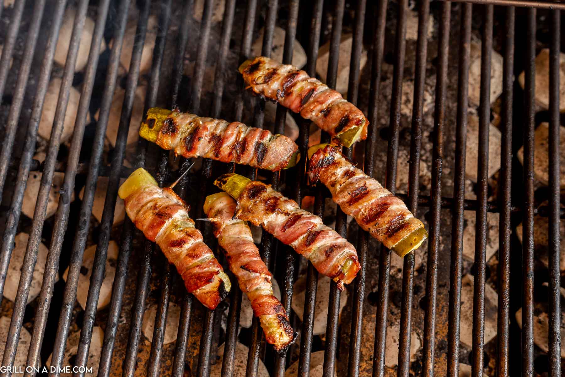 Grilled bacon-wrapped jalapeno poppers on a white plate, fresh and smoky for appetizers.