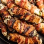 Bacon-wrapped jalapenos stuffed with cheese, grilled to perfection for tasty appetizer.