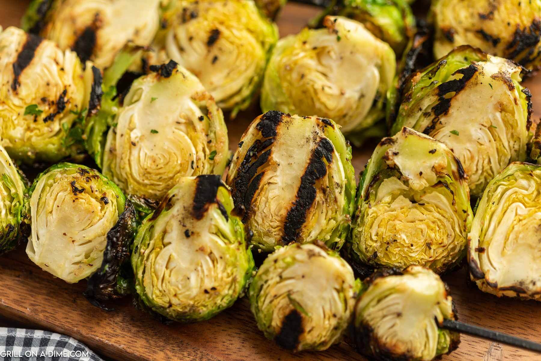 Grilled Brussel Sprouts on skewers on a wooden platter