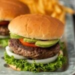 Hamburgers with lettuce, tomato and avocado on a tray.