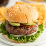 Juicy grilled hamburger with fresh avocado slices and crispy lettuce on a sesame seed bun