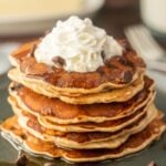 A stack of pancakes topped with whipped cream and chocolate chips.