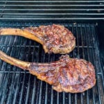 Two large steaks on a grill with a grill pan.