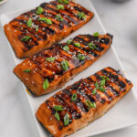 Grilled Salmon on a platter topped with green onions and sesame seeds