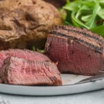 A steak on a plate with a side of potatoes.