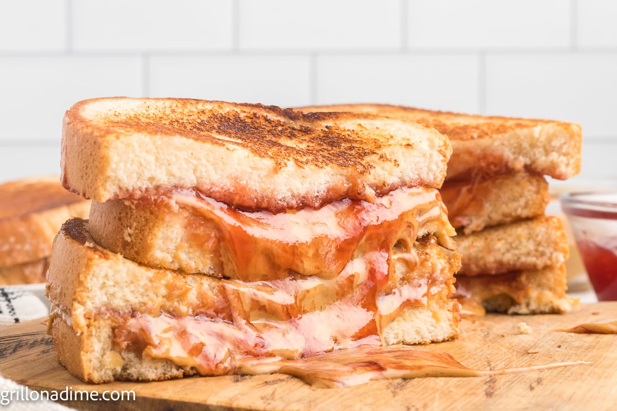 Melted peanut butter and jelly sandwich cut in half on a wooden board