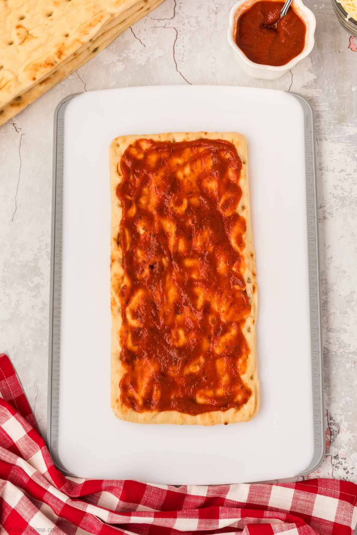 Spreading pizza sauce on flatbread pizza
