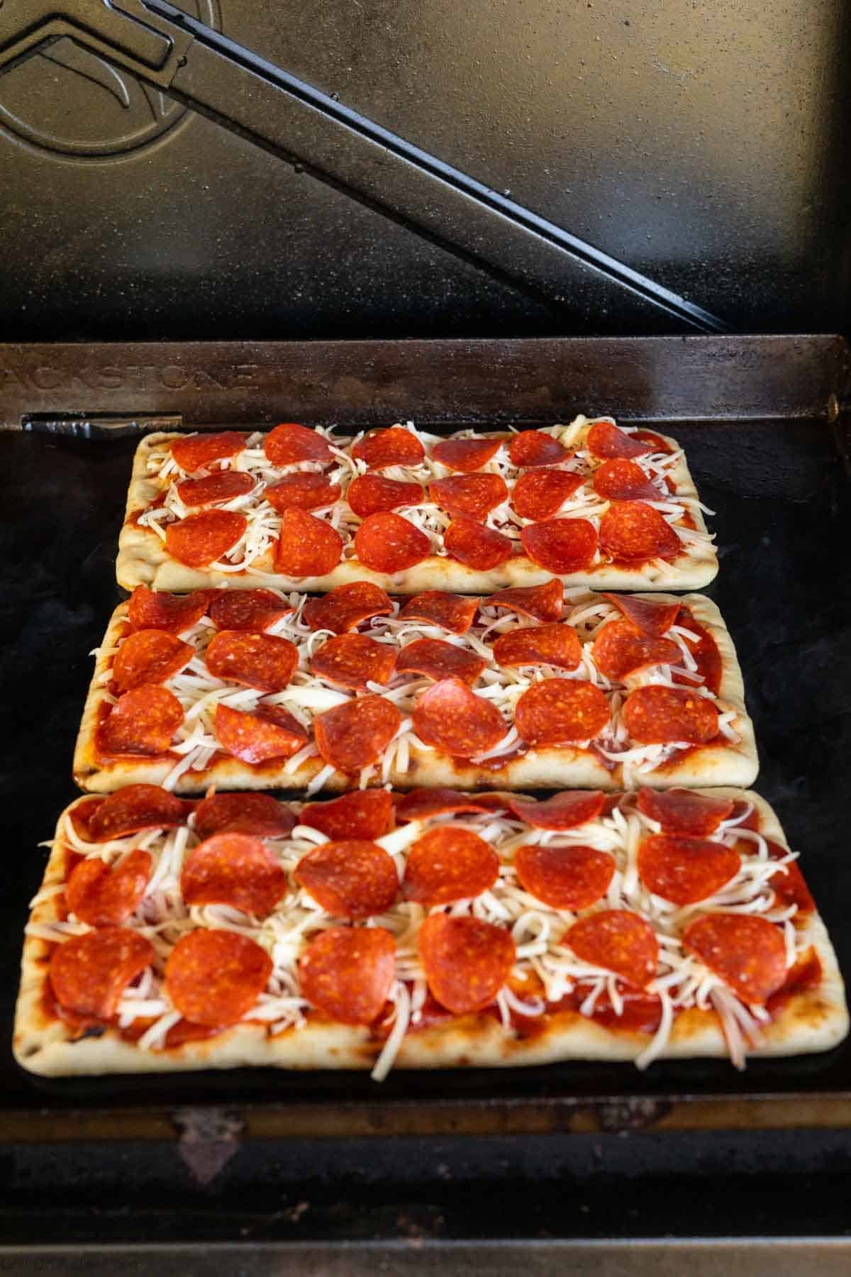Placing flatbread pizzas on Blackstone flat top