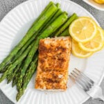 Grilled Mahi Mahi on a plate with a side of asparagus and fresh lemon slices
