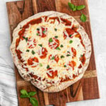 A homemade pizza on a wooden cutting board.