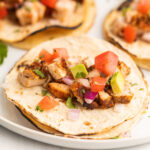 Grilled Chopped Chicken on tortillas topped with dice onion, avocado and tomatoes