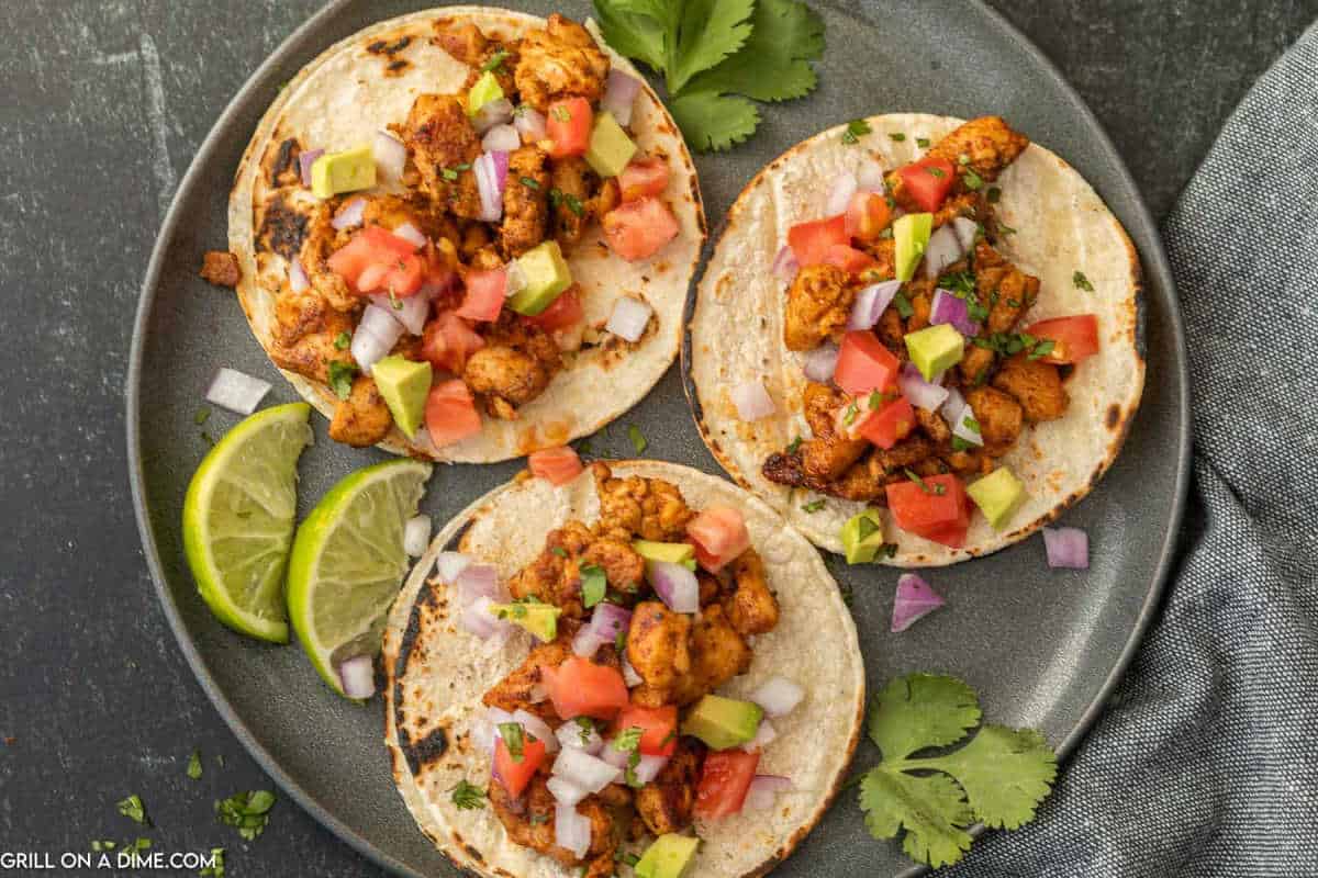 Chicken Street Tacos topped with diced avocados on a plate.