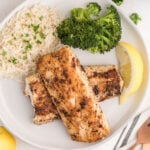 Baked mahi mahi with rice, broccoli, and lemon on white plate, healthy seafood dinner recipe.