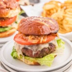 juicy cheeseburger with lettuce, tomato, caramelized onions, melted cheese, and dipping fries on side