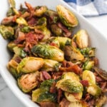 A white bowl filled with brussels sprouts and bacon.