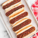 A tray of hot dogs with toppings on them.