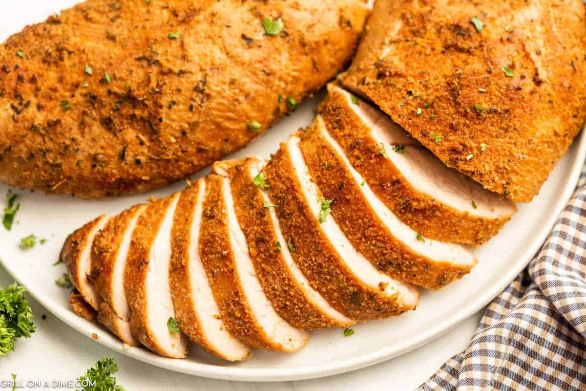 Juicy baked turkey breasts with crispy seasoned coating, sliced and garnished with fresh herbs.