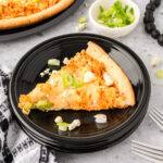 Slice of Buffalo Chicken Pizza topped with green onions on a plate