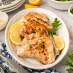 Grilled Grouper stacked on a white platter with lemon wedges on the side