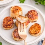 Cooked Scallops on a plate with one scallop pierced with a fork.