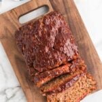 Sliced meatloaf on a cutting board with a knife.
