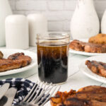 A glass jar filled with 3 Ingredient Steak Marinade sits on a white table.