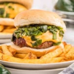 A cheeseburger with green onions and cheese on a plate.