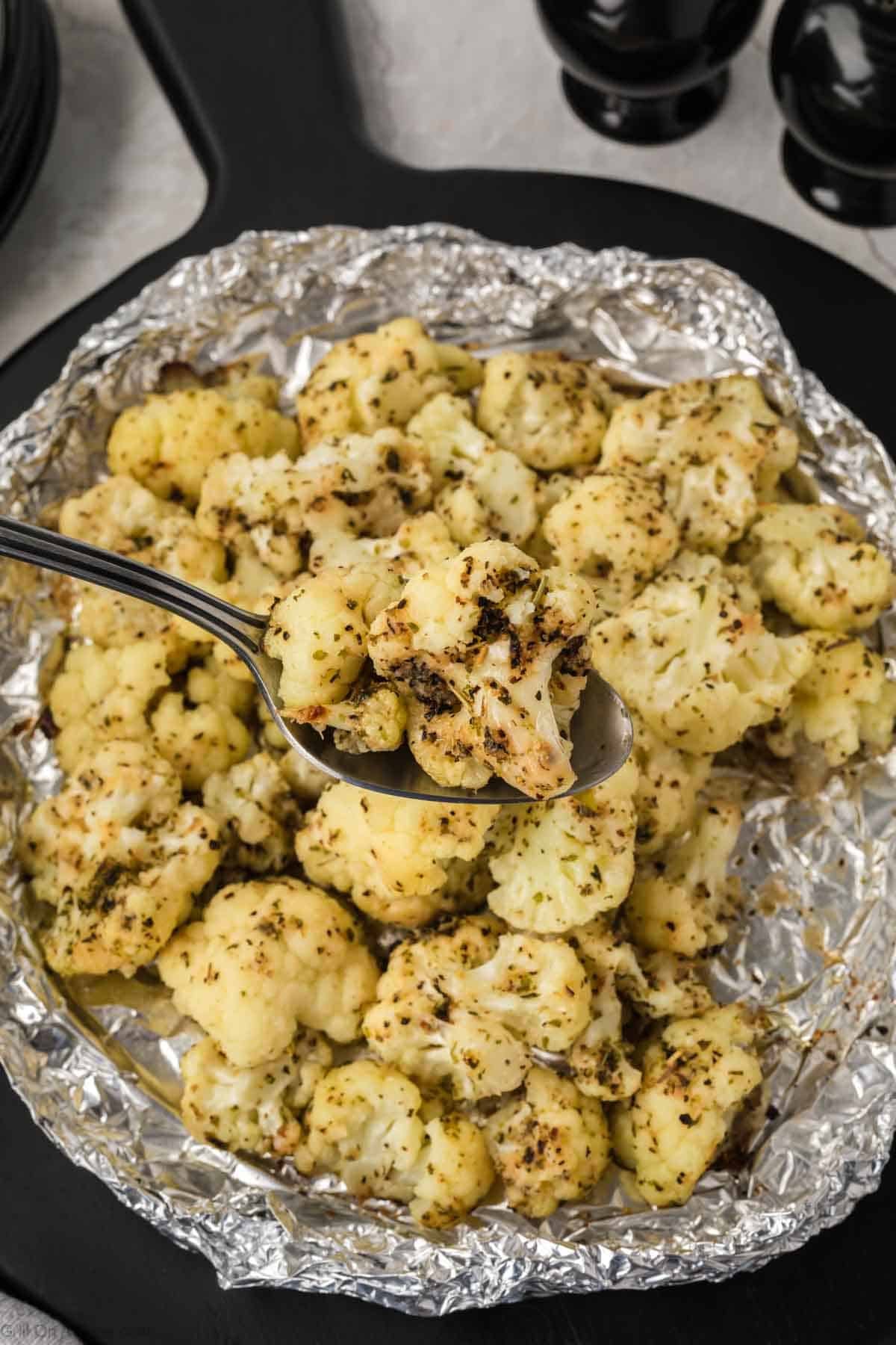 A pan filled with roasted cauliflower and a spoon.