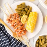Grilled Shrimp Kabobs on a plate with corn on the cob and green beans on the side