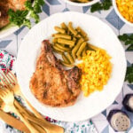 Grilled pork chops on a plate with green beans and corn