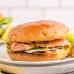Grilled salmon sandwich with lettuce and creamy sauce on toasted bun.