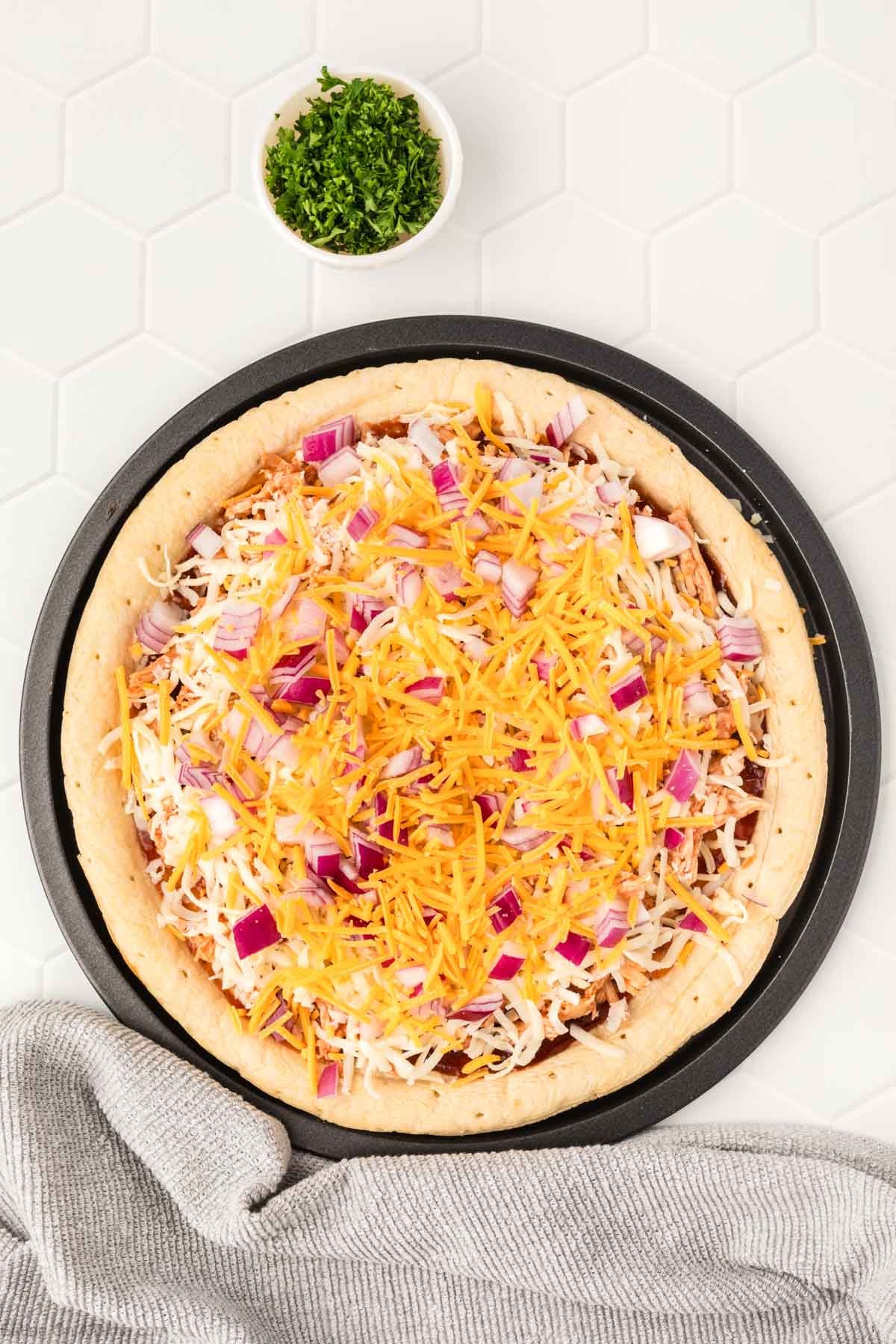 Pizza crust topped with shredded cheese, red onions